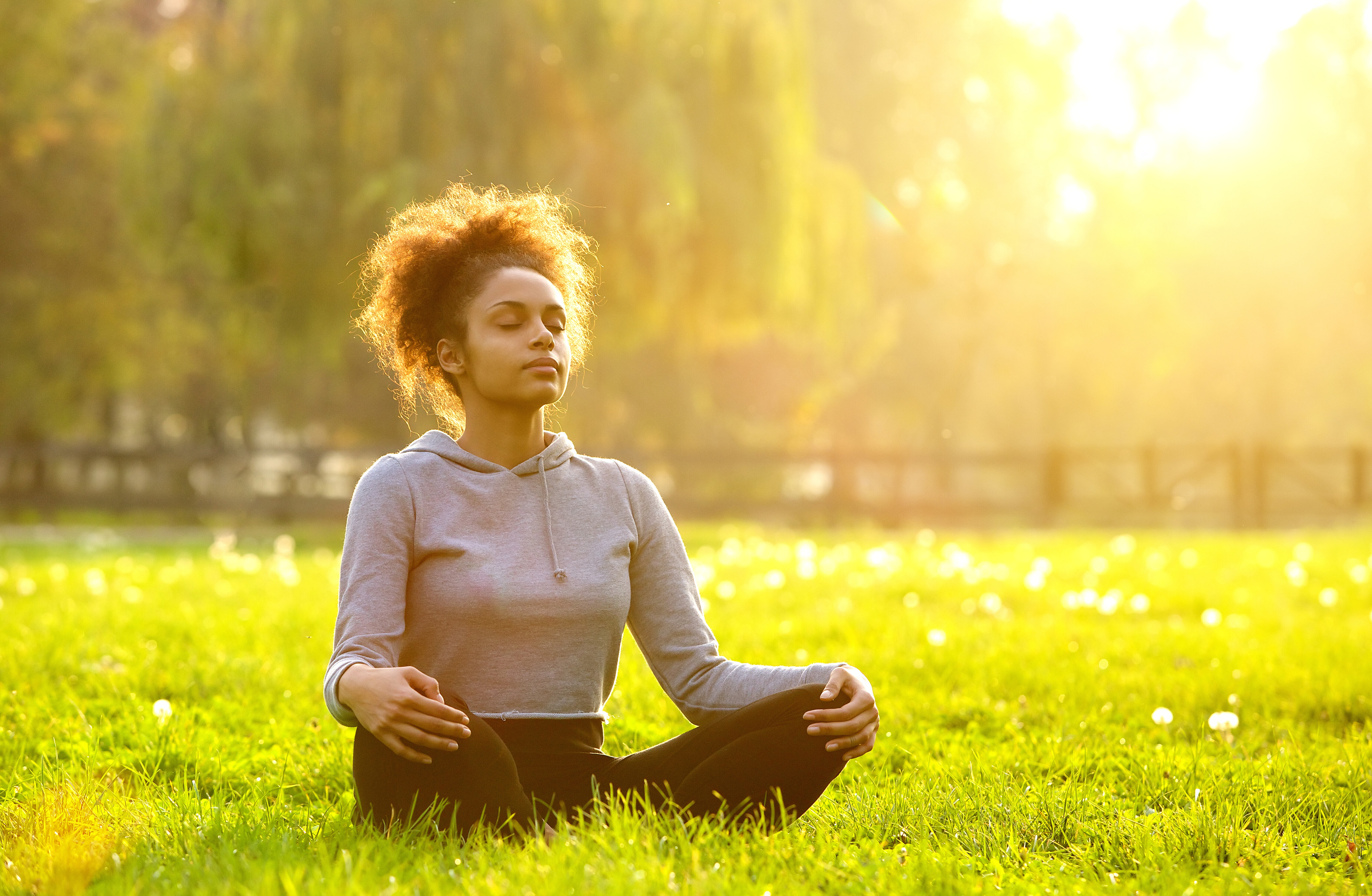 Mulher sentada na grama meditando.