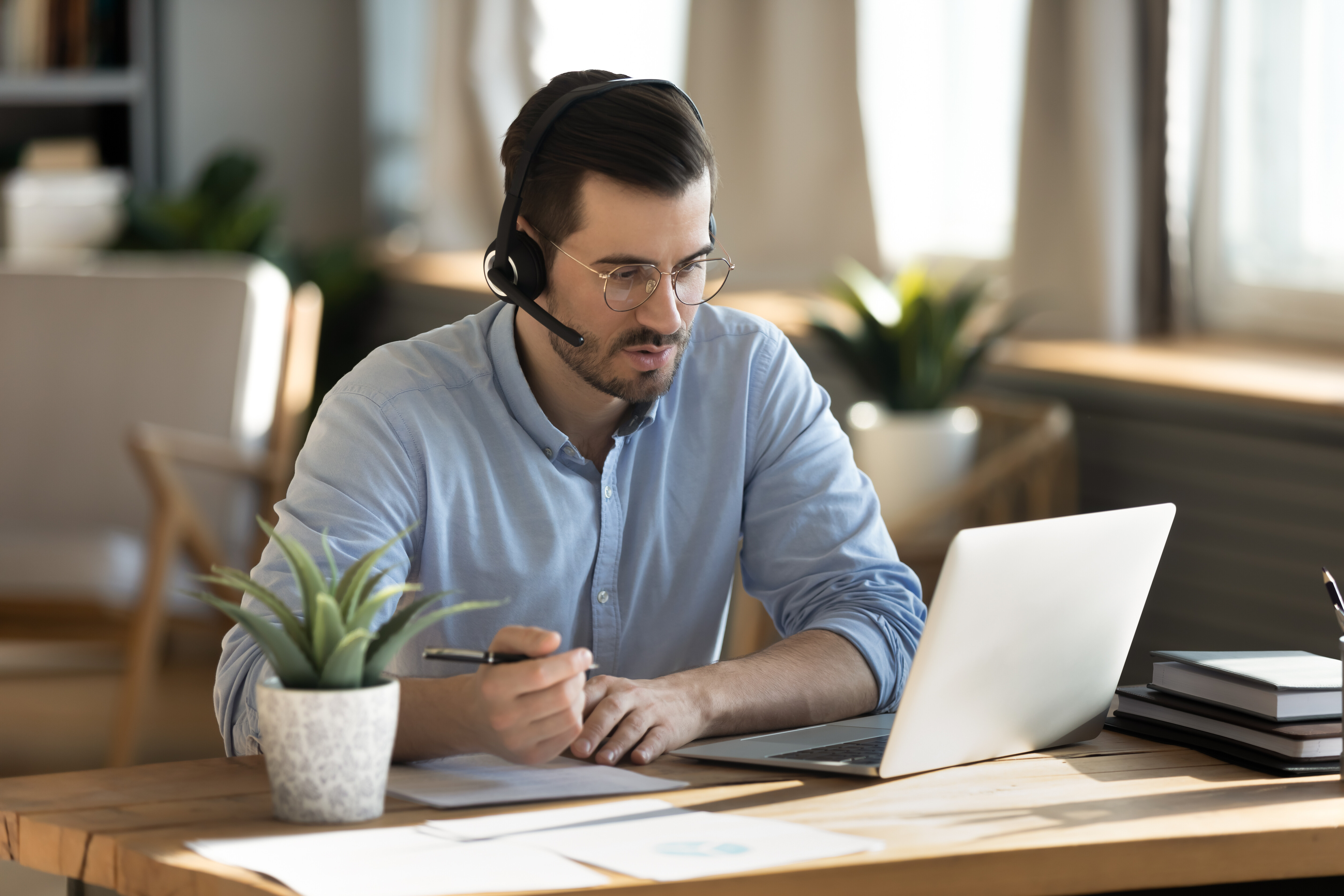 A imagem mostra um homem ao computador usando fones de ouvido.